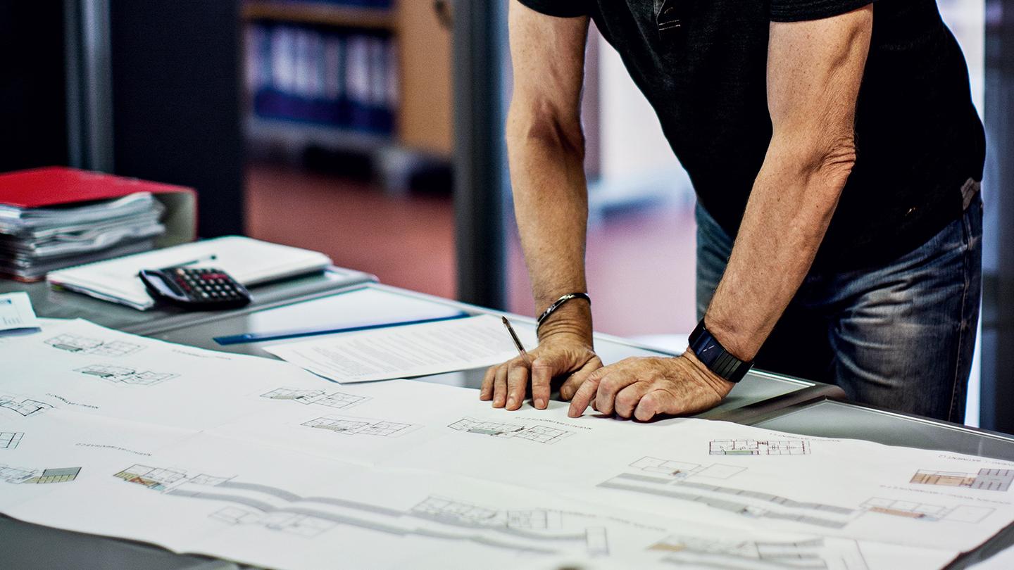 Un homme est en train de travailler sur des plans d'architectes dans un bureau