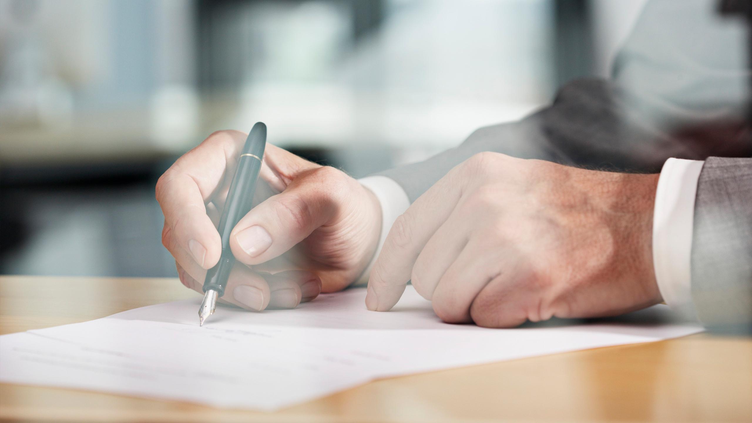 Un homme est en train de signer un document officiel chez le notaire 