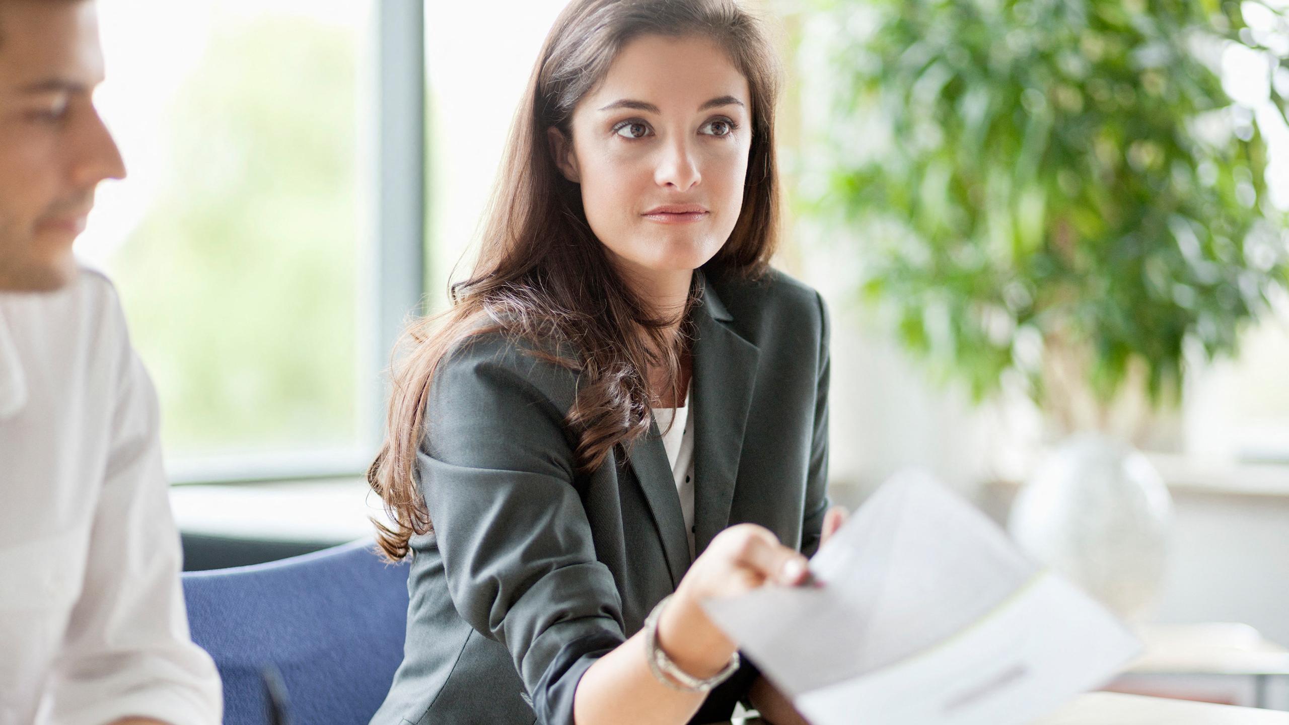 Une femme tend un document à une personne assise en face d'elle