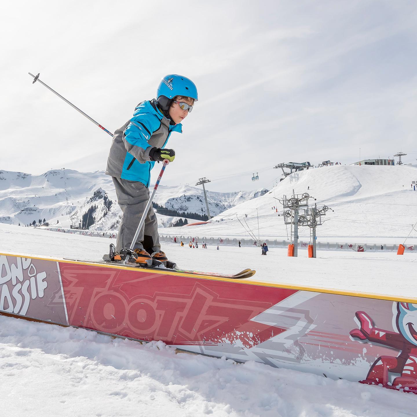 Un enfant est en train de glisser à skis sur un tremplin du snowpark de Samoëns