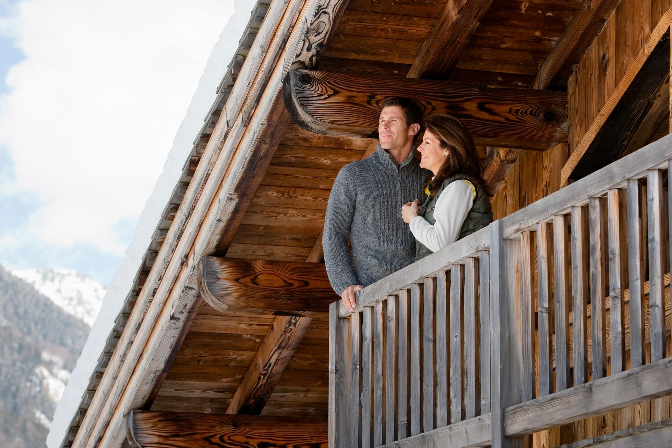 couple sur le balcon d'un chalet admirant la vue