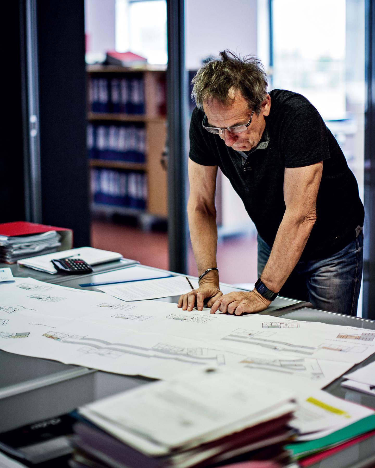 Un homme est en train de travailler sur des plans d'architectes dans un bureau