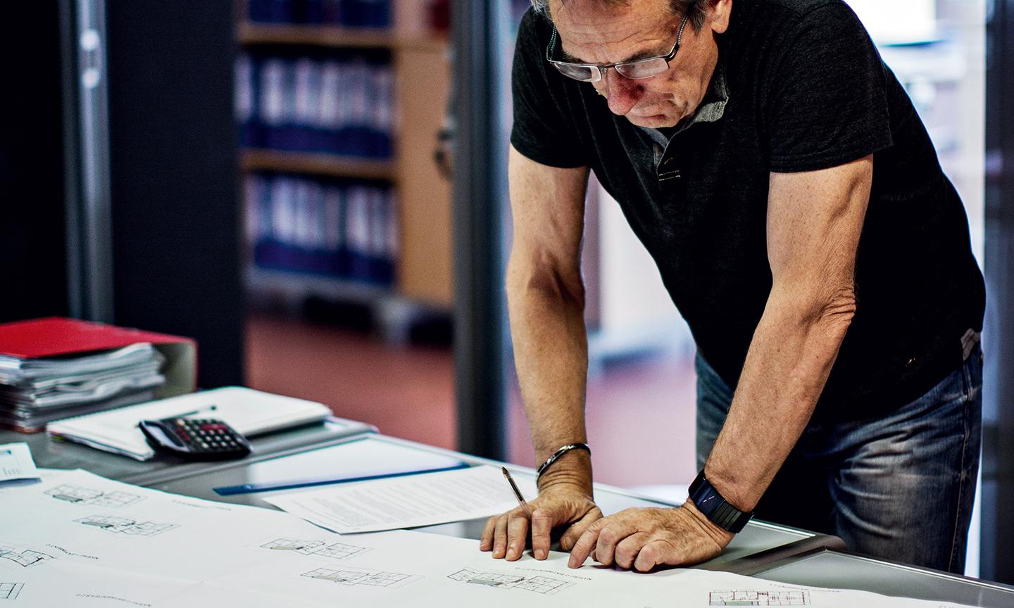 Un homme est en train de travailler sur des plans d'architectes dans un bureau